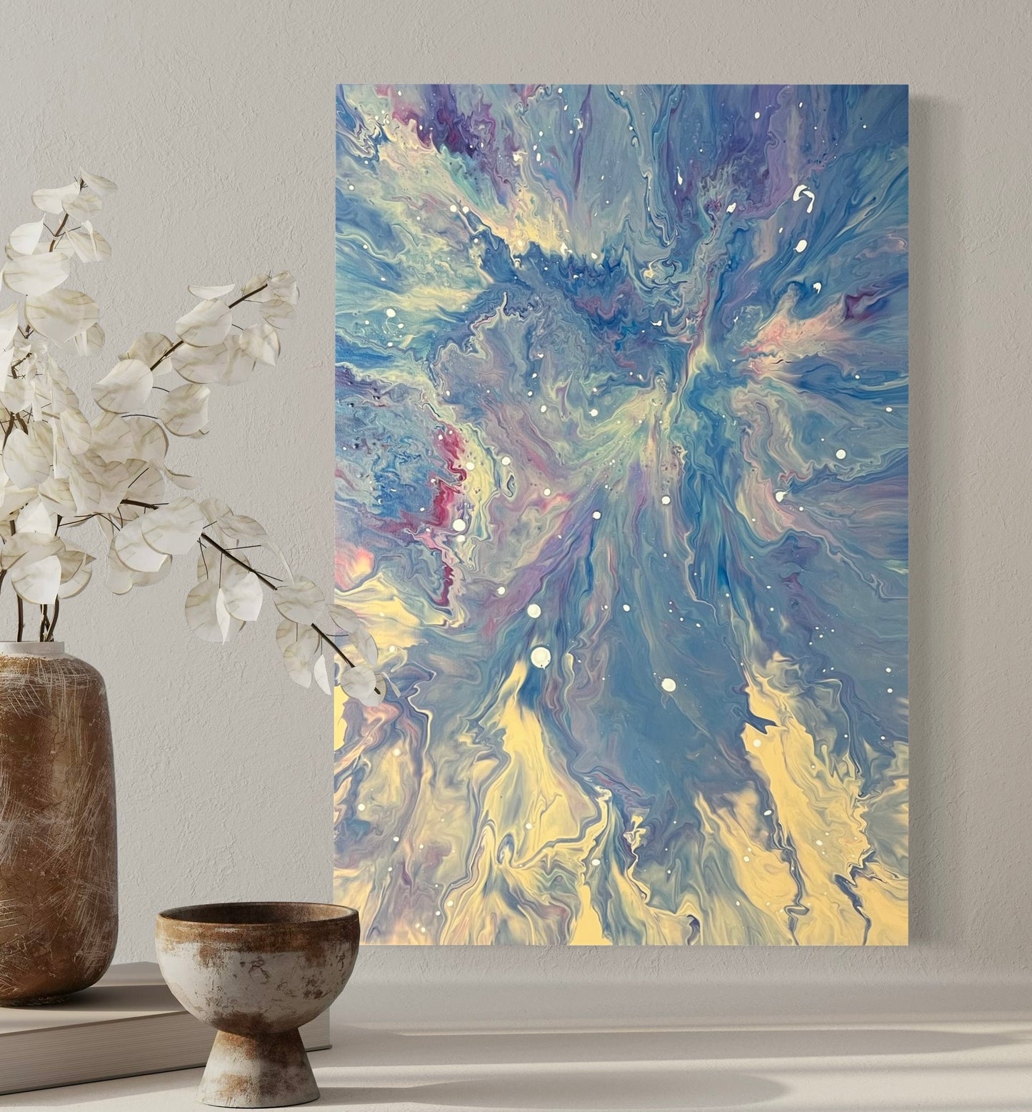 Abstract acrylic painting in blue, white and pastel tones with dynamic flow technique and white speckles - Modern fluid art artwork with galactic flair on a light background.
